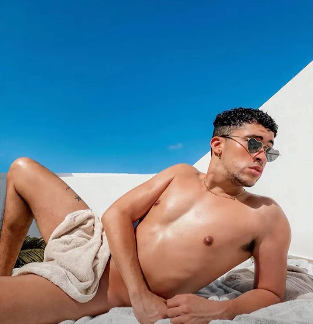 Bad Bunny covered just by the small towel and wearing heart-shaped sunglasses