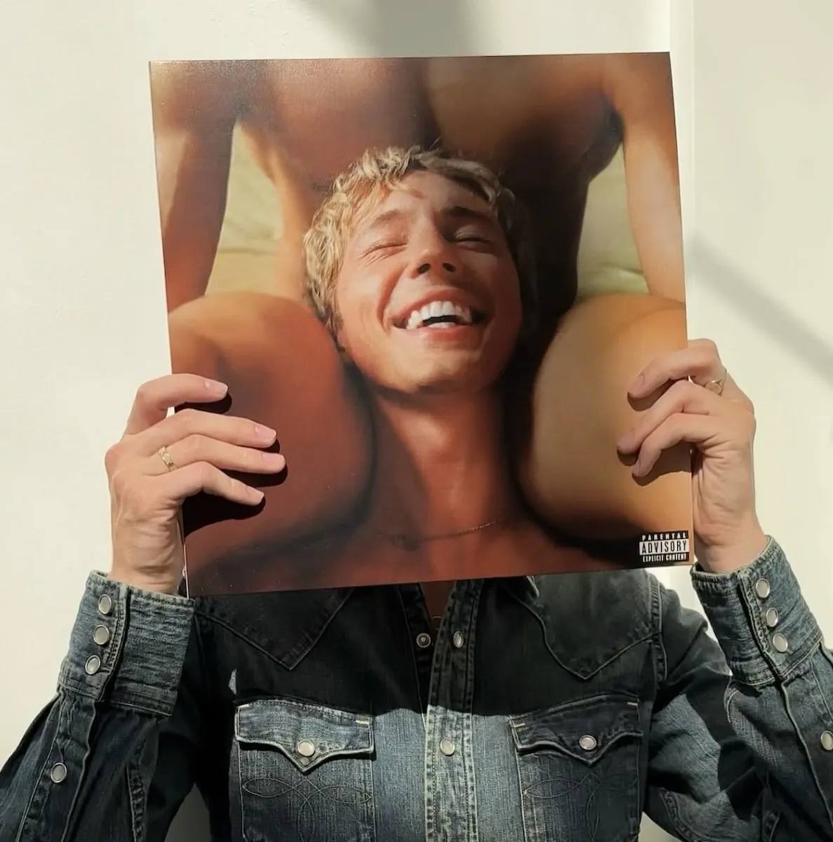 Troye Sivan holding his album "something to give each other"