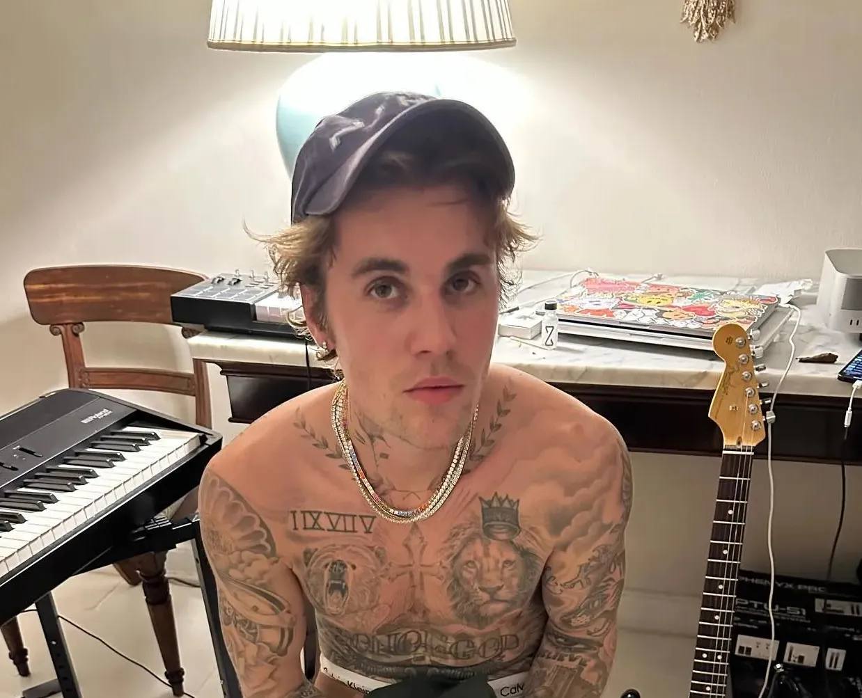 Justin Bieber with naked torso and a baseball hat in a studio