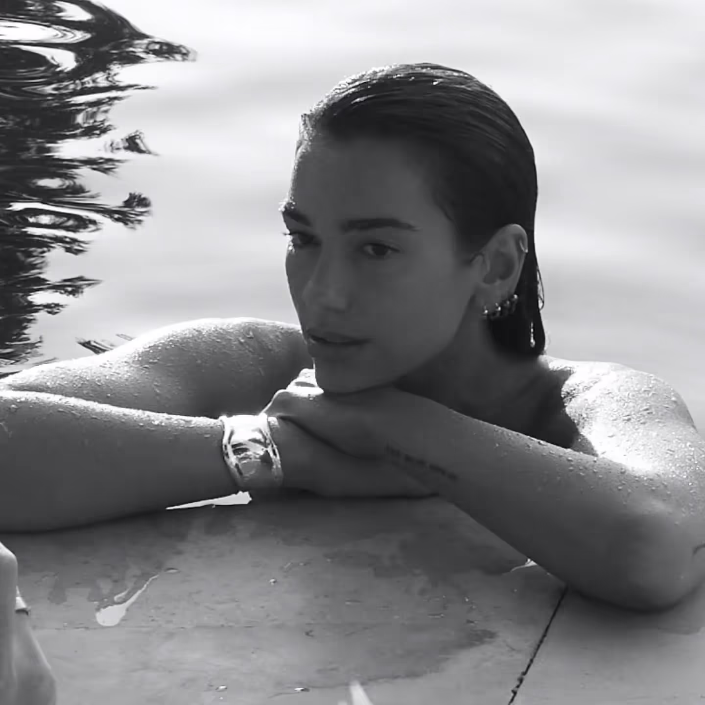 Dua Lipa submerged in a pool, black and white