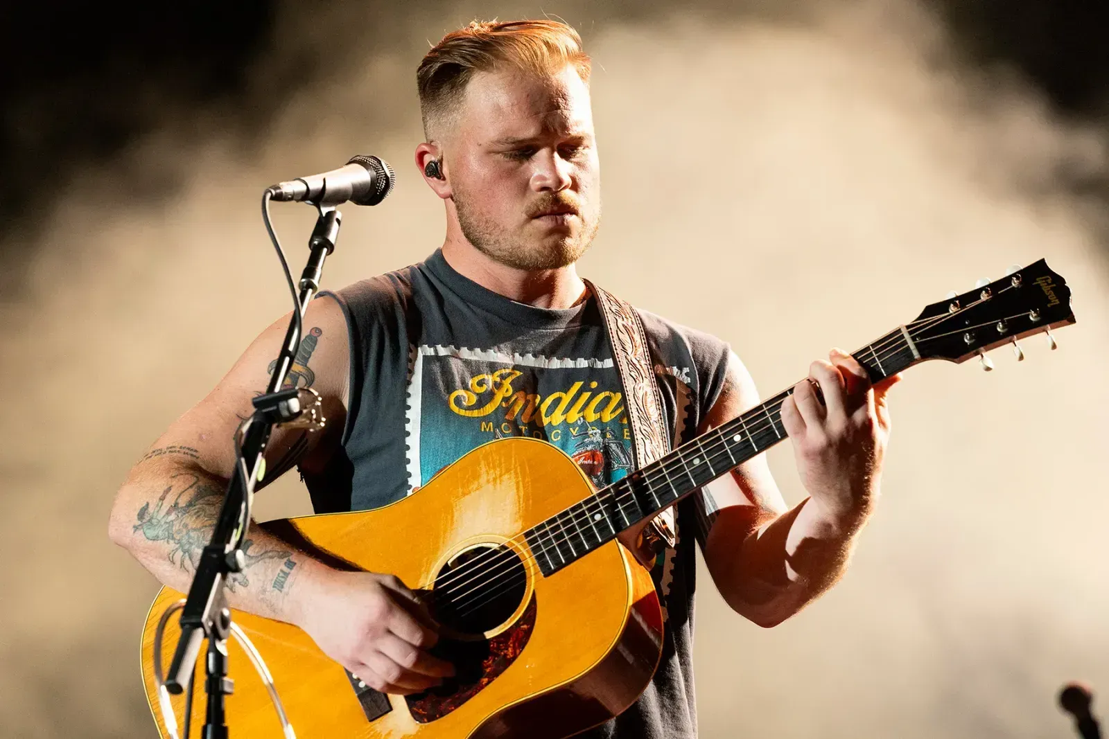 Zach Bryan performing on stage, playing guitar
