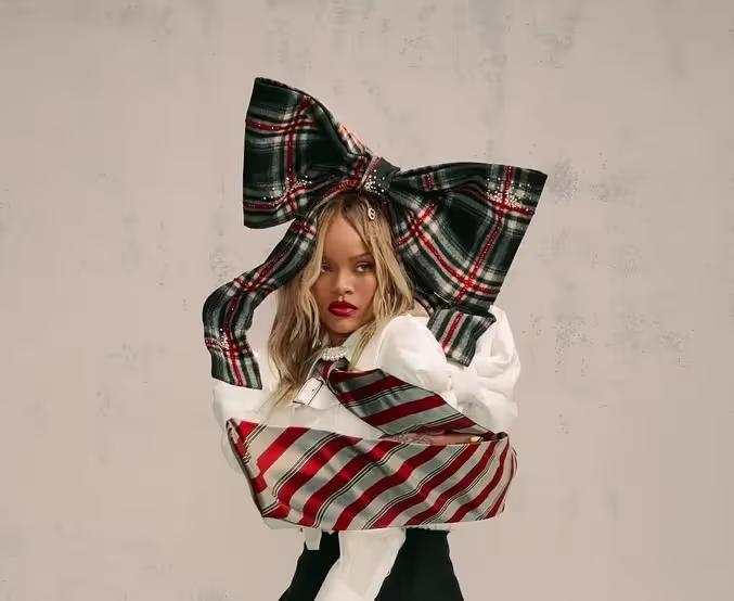 Portrait of Rihanna wearing white shirt, oversized red and black bow and wrapped in red and black oversized tie in PumaxFenty campaign, 'Creeper Phatty'