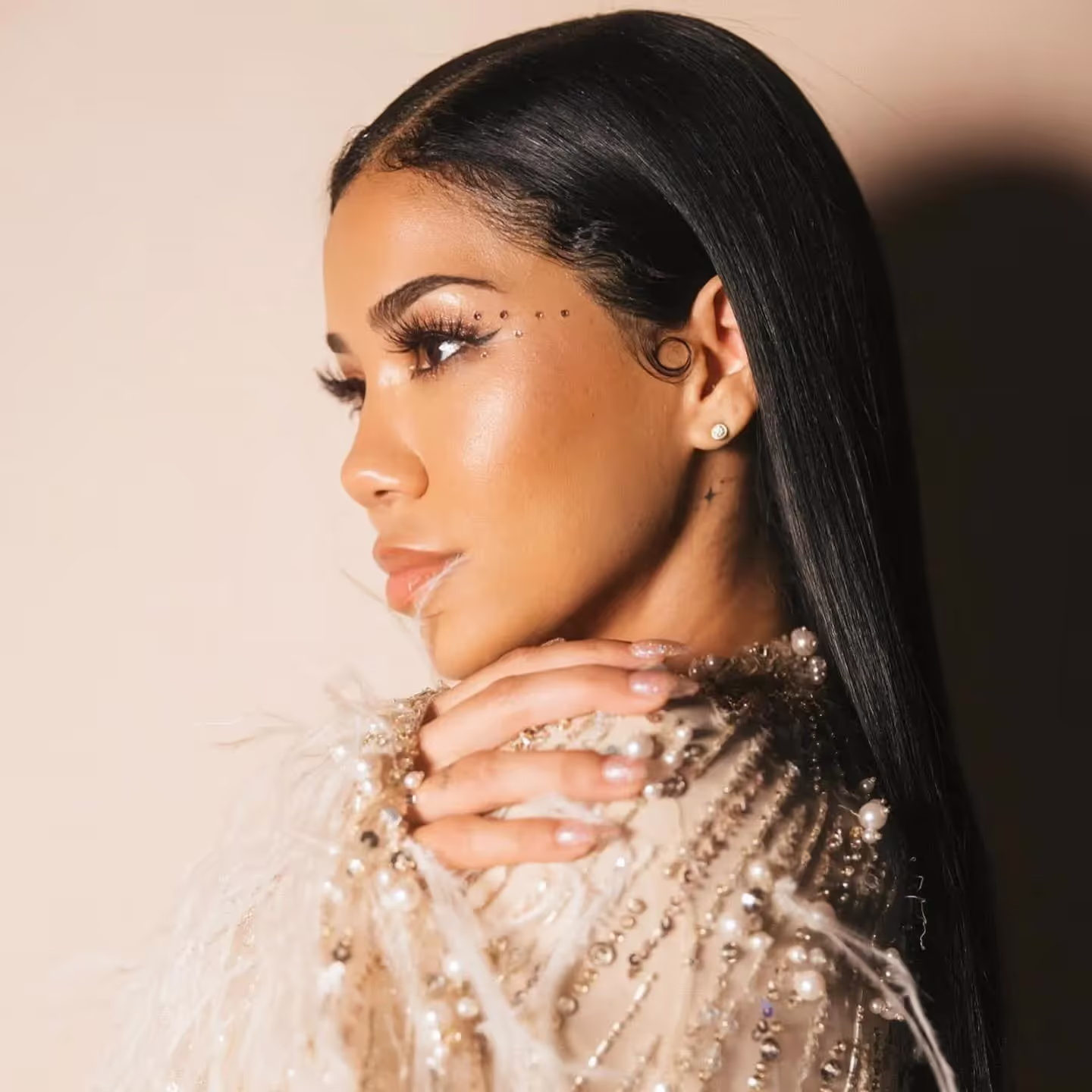 Jhene Aiko's portrait 2024, slick hairstyle, neutral make up and beaded nude dress with feathers