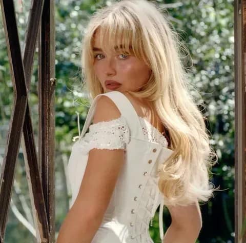 Sabrina Carpenter wearing a white lacy corset, looking over her shoulder, celebrating 'Short n' Sweet' RIAA Platinum certification.