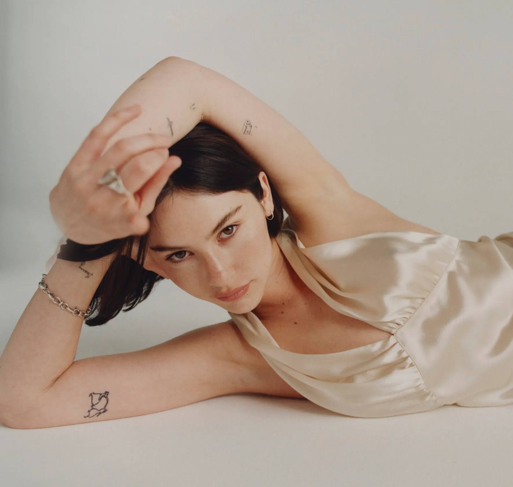 Gracie Abrams posing in ivory silk gown, short bob, via Interview.