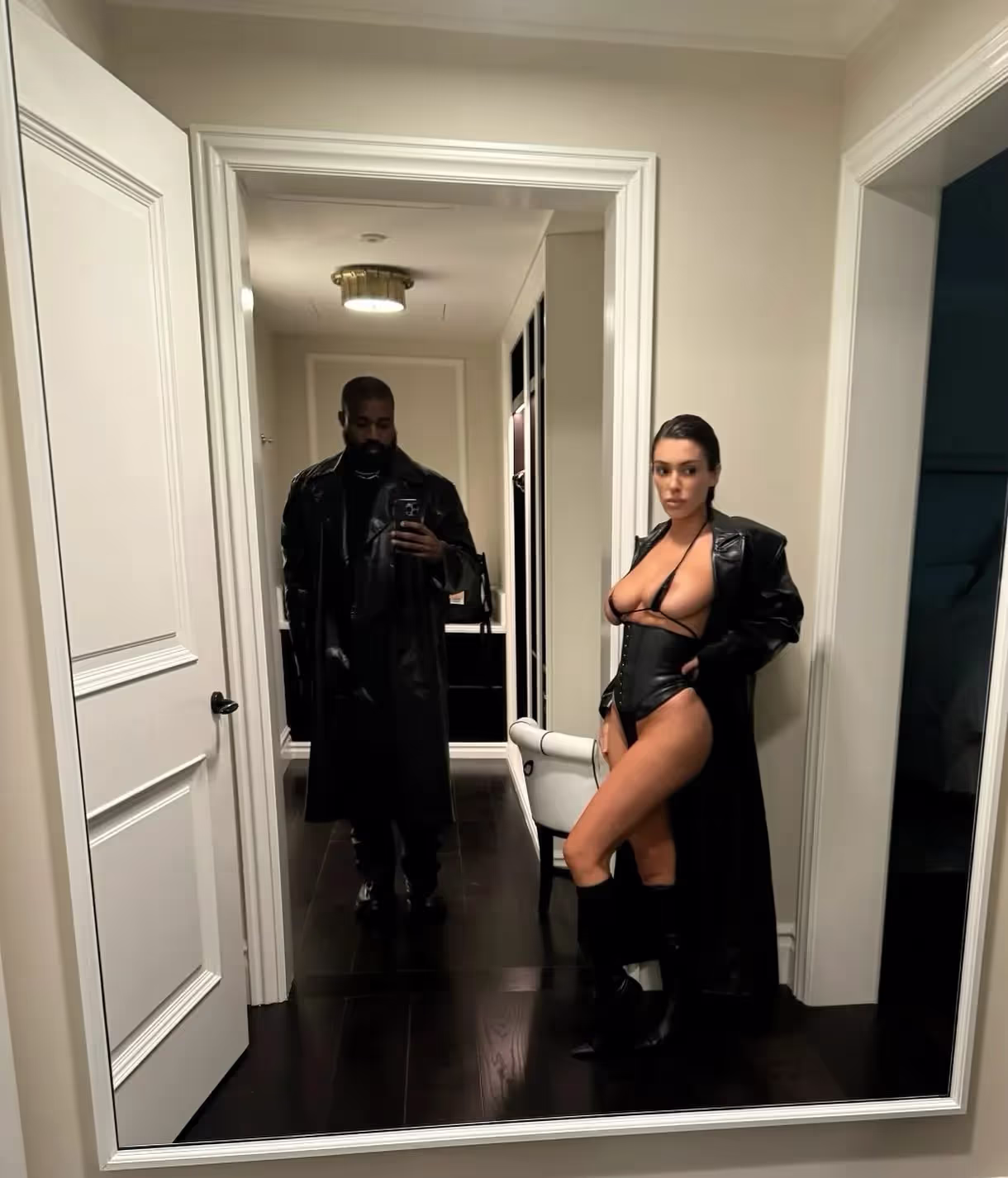 Kanye West (Ye) and his wife Biance Censorinwearing Matrix-like black coat over Bianca's very provocative black lingerie