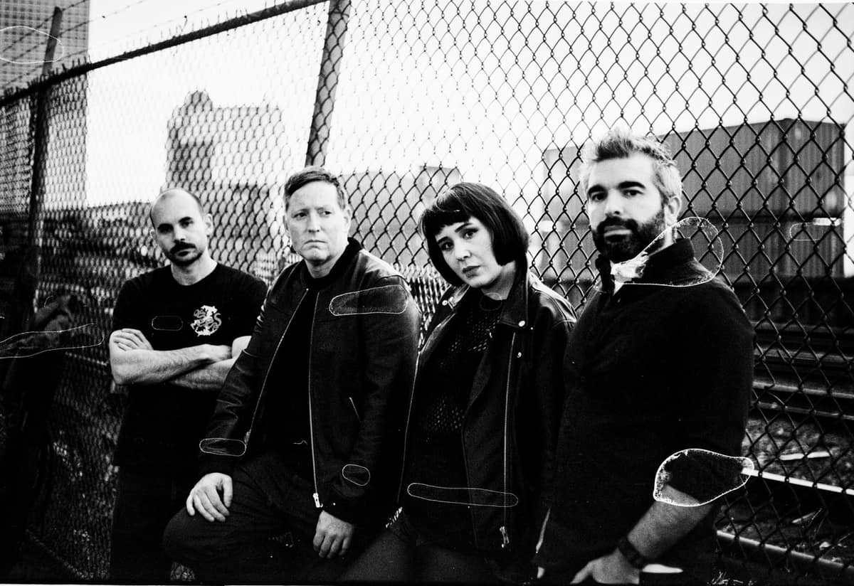 The Haptics, all four members by the fence, black and white